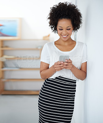 Buy stock photo Portrait of an attractive young woman sending a text message while standing in an office