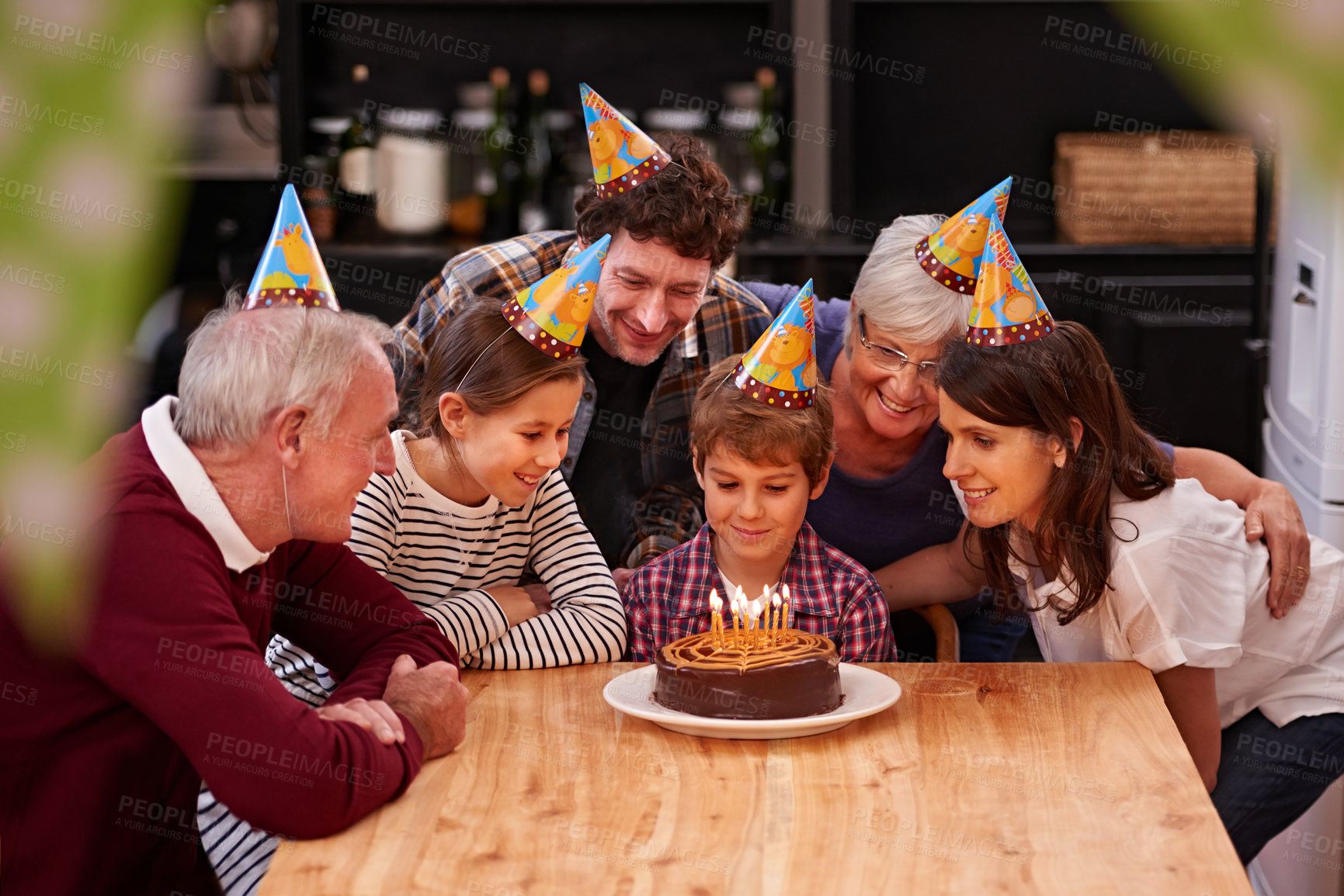 Buy stock photo Family, birthday cake and candle with kid, parents and grandparents together with cake and wish. Happy, smile and dessert with children and celebration with event food and party hats at a table