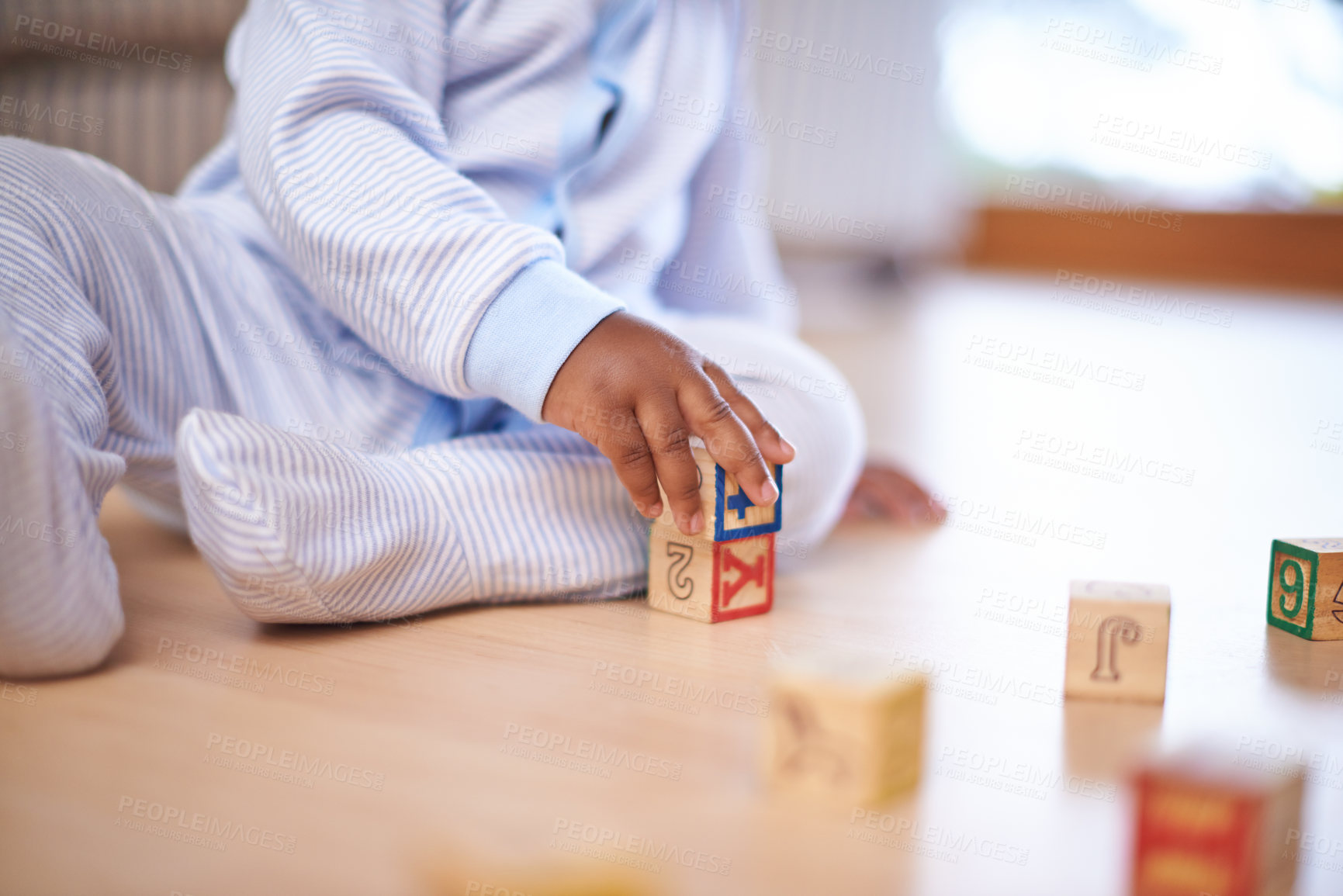 Buy stock photo Cropped shot of a baby boy playing with wooden building blocks on the floor