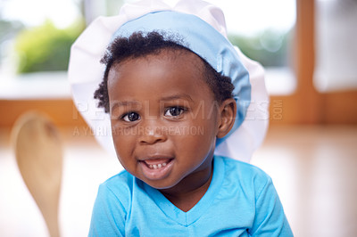 Buy stock photo Black baby, portrait and chef hat in house with spoon, blue tshirt and jeans for child development, learning and cognitive skill. African child, smile and toque in home with clothes for growth