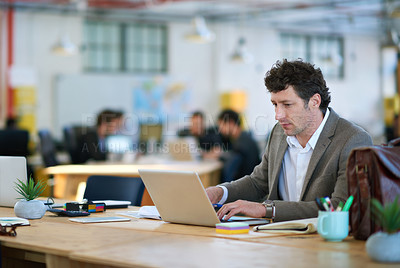 Buy stock photo Shot of a man working on a laptop in a large office