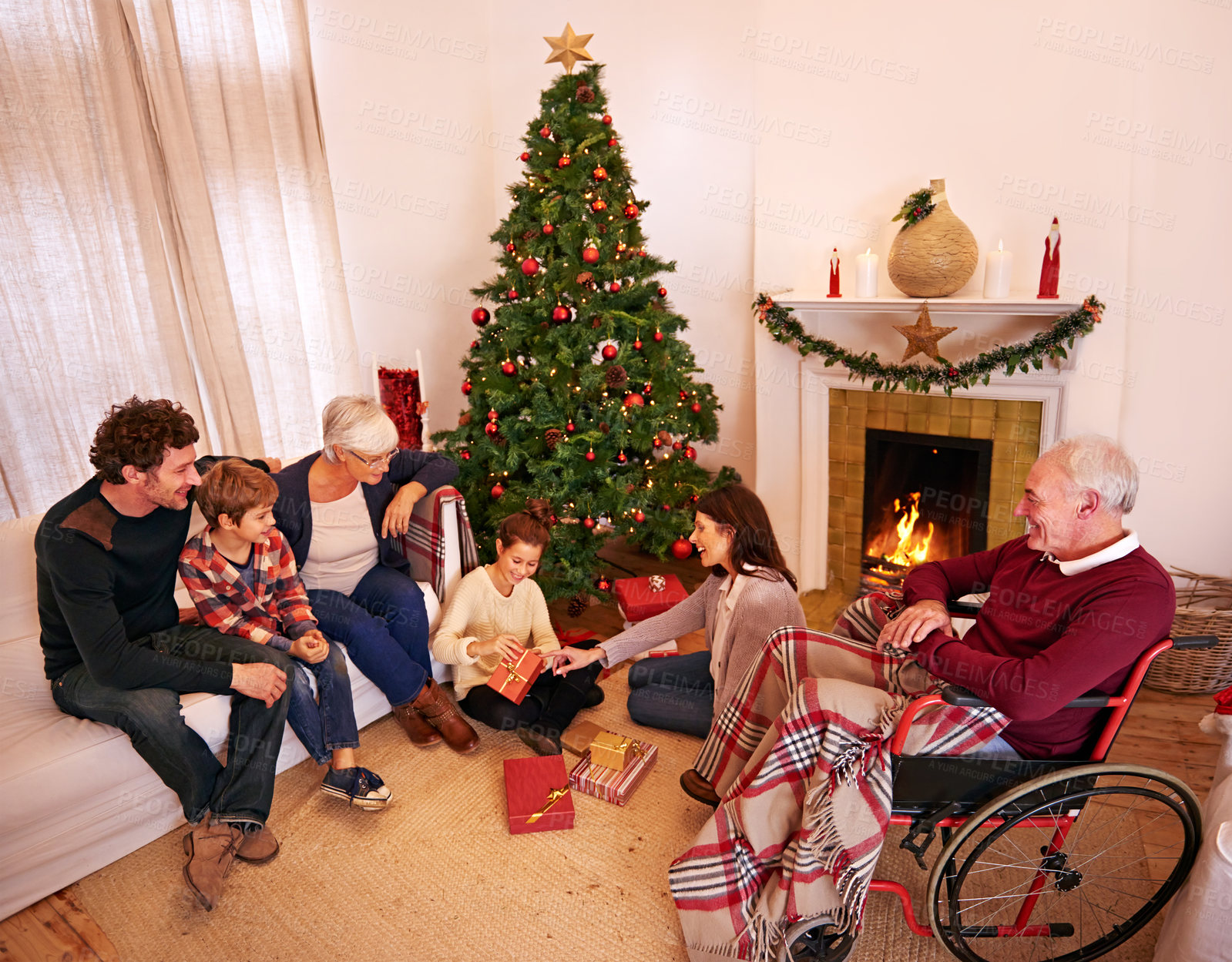 Buy stock photo Big family, Christmas and giving present or gift with children, parents and grandparents together for love, care and celebration. Men, women and kids in house at fireplace to celebrate holiday