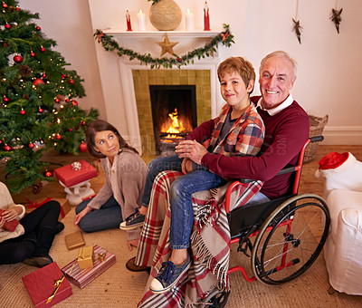 Buy stock photo Family, christmas and love of child, grandpa and mother together to open gift or present together at fireplace in home living room. Senior man in wheelchair with boy and woman to celebrate holiday