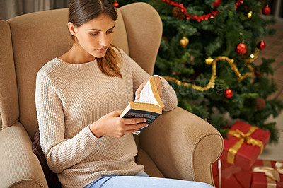 Buy stock photo Shot of a beautiful young woman reading a book at home during the Christmas holidays