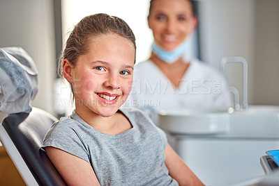 Buy stock photo Shot of a young girl sitting in a dental chair with her dentist in the background