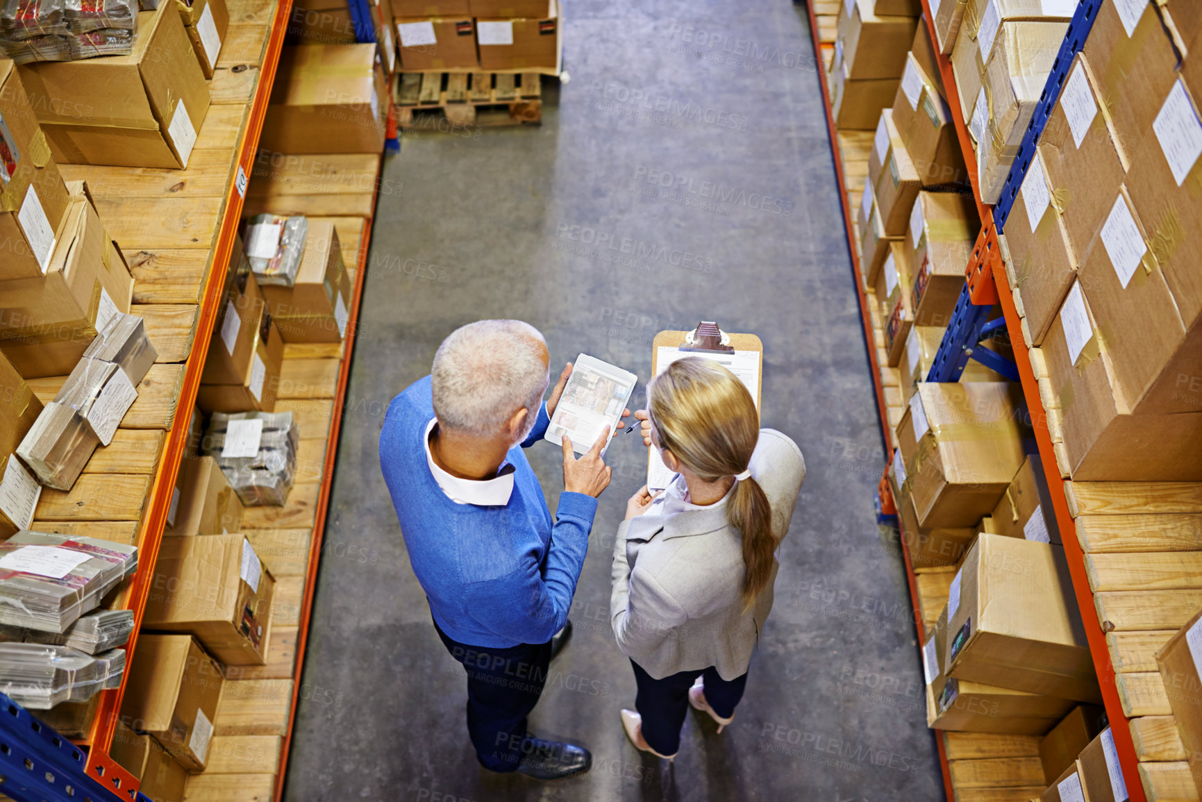 Buy stock photo High angle shot of a two managers working on a digital tablet in a warehouse