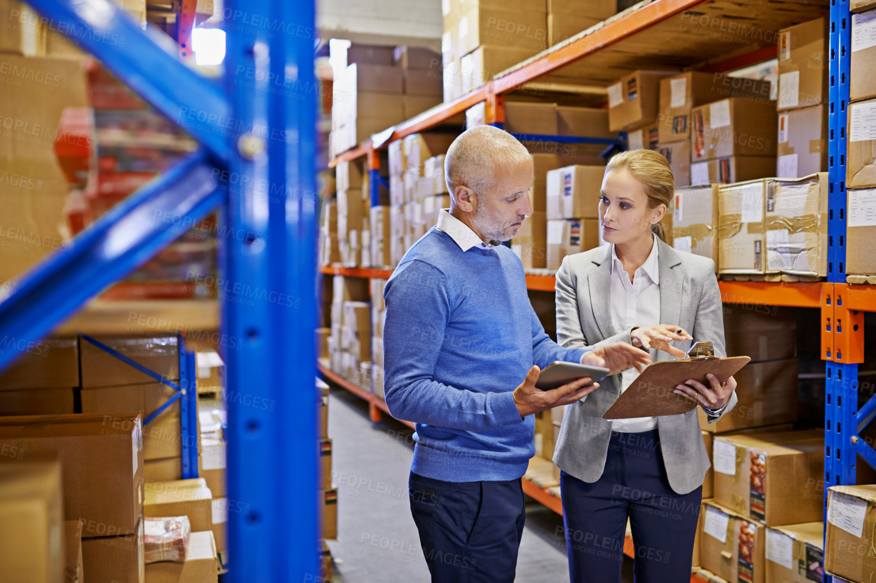 Buy stock photo Shot of a man and woman inspecting inventory in a large distribution warehouse