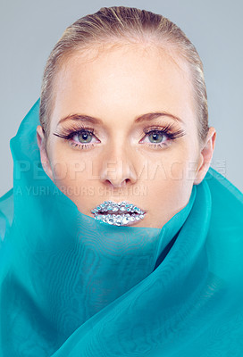 Buy stock photo Studio portrait of a beautiful young woman with sparkling lips wrapped in blue material