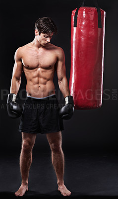 Buy stock photo Boxing, man and training in studio with punching bag for workout, exercise or fight competition with dark background. Gloves, boxer and serious male athlete for confidence, martial arts and fitness