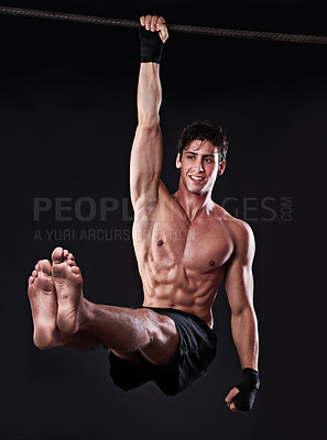 Buy stock photo Studio shot of a young man doing pull-ups from a bar