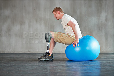 Buy stock photo Shot of a young amputee working out on a swiss ball