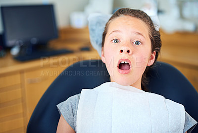 Buy stock photo Shot of a young girl looking terrified while sitting in a dentist's chair
