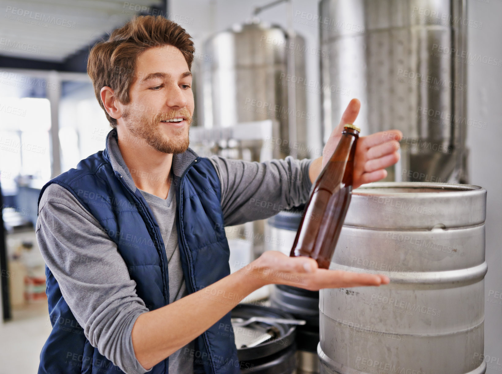 Buy stock photo Brewery, man and bottle with tank in factory with confidence, sample and container machine for manufacturing. Industrial, worker and smile in distillery with assembly line for brewing in warehouse