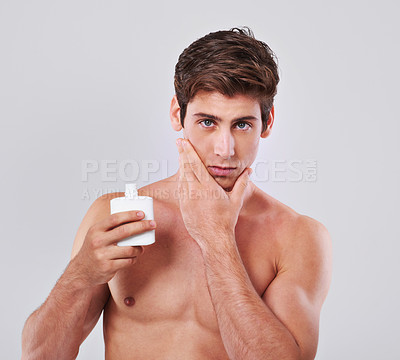 Buy stock photo Young man, portrait and aftershave with cosmetics for skincare or lotion on a gray studio background. Face of handsome male person or model with beauty creme or container for hygiene on mockup space