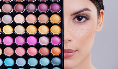 Buy stock photo Studio shot of a beautiful woman with makeup palettes in front of her face