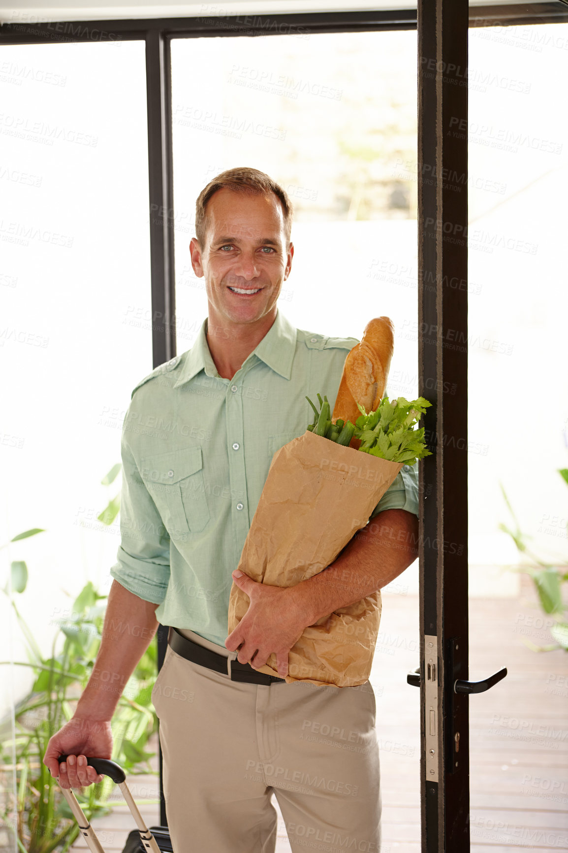 Buy stock photo Smile, man with groceries bag in portrait with suitcase for work trip or holiday or vacation in California. Happy person, vegetables and bread as food for breakfast, lunch or dinner in apartment