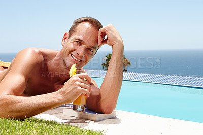 Buy stock photo Portrait of a smiling man enjoying the sunshine by the pool while holding a drink