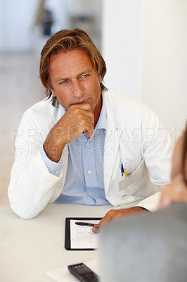 Buy stock photo Focused plastic surgeon listening to patient in a consultation at his office. Serious male medical specialist in a lab coat talking about cosmetic surgery concerns and risks at a hospital or clinic