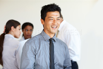 Buy stock photo Businessman, smile and thinking in office with team building and professionals at workplace. Asian, male person and employees with cheerful, happy and future for business, company and startup

