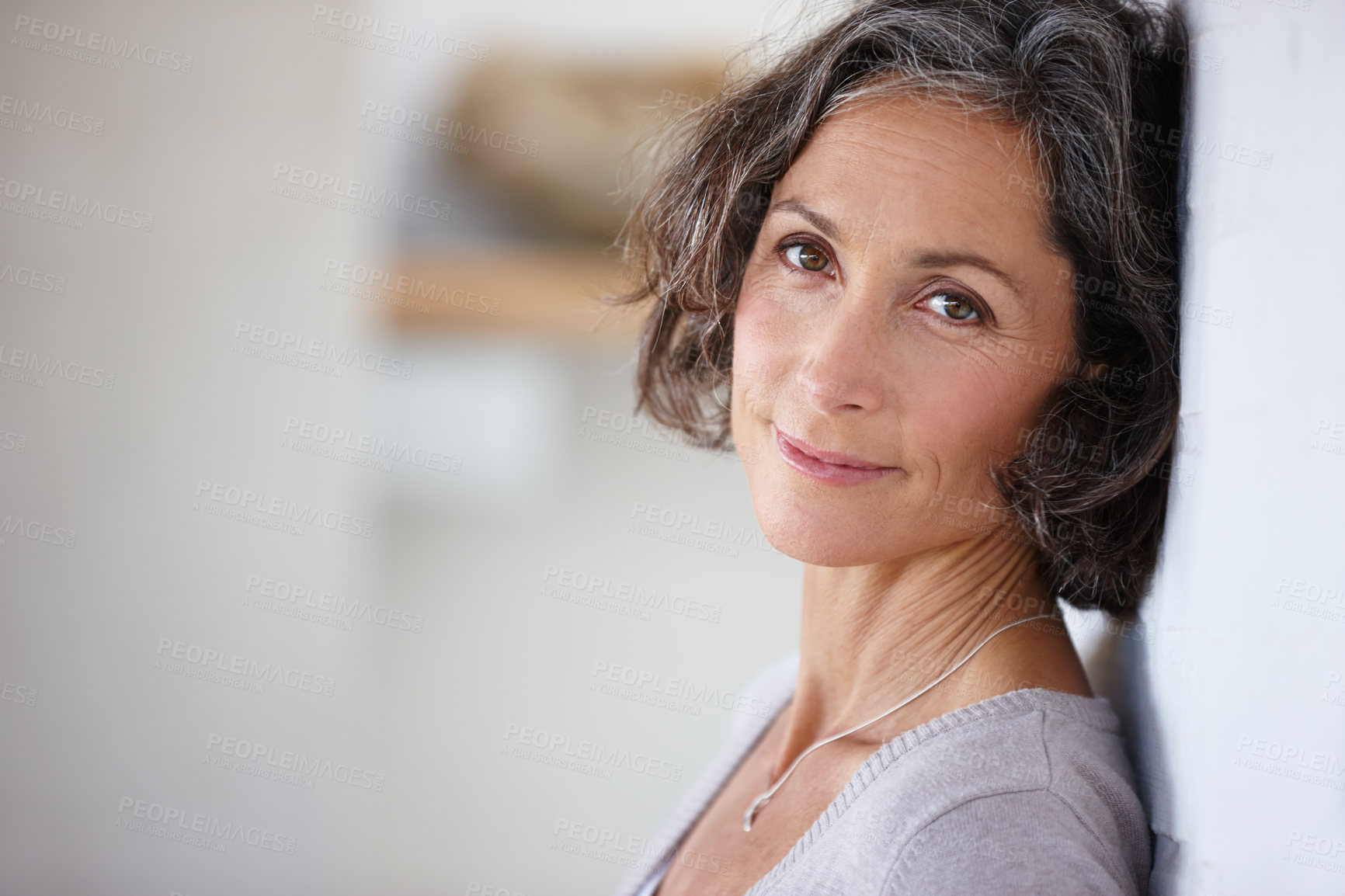 Buy stock photo Shot of an attractive mature woman leaning against a wall