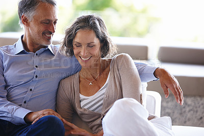 Buy stock photo Shot of an affectionate mature couple sitting inside on the sofa
