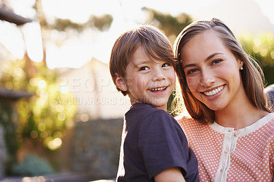 Buy stock photo Portrait of a happy young mother and her adorable son standing outside in the garden