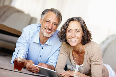 Buy stock photo Portrait of a happy mature couple lying on the floor and using a digital tablet