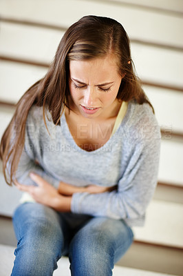 Buy stock photo Stomach pain, stress and woman in a house with pms, gas or constipation, virus or gut health problem. Stairs, belly ache and female person frustrated by endometriosis, crisis or menstruation cramps