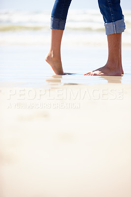 Buy stock photo Cropped shot of a couple standing close to the water's edge on a warm summer's day