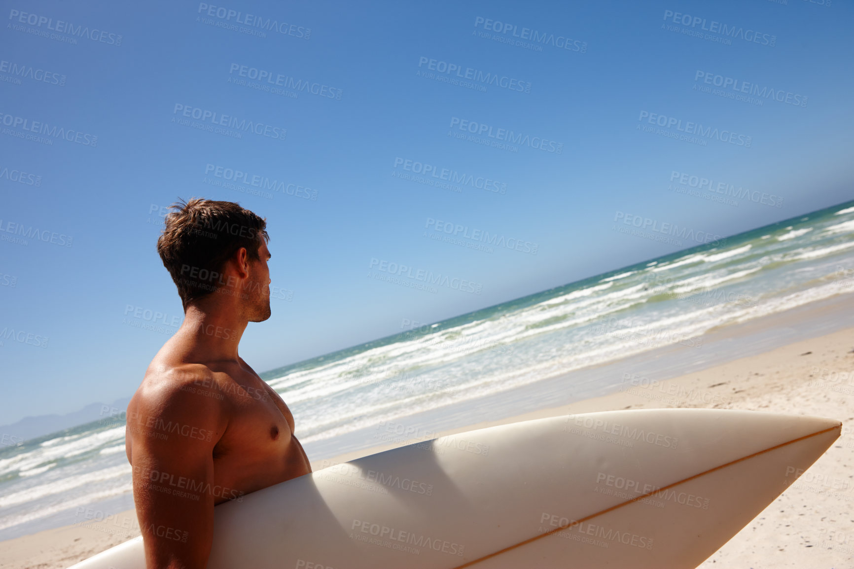 Buy stock photo Head and shoulders shot of a young man standing on the beach with his surfboard