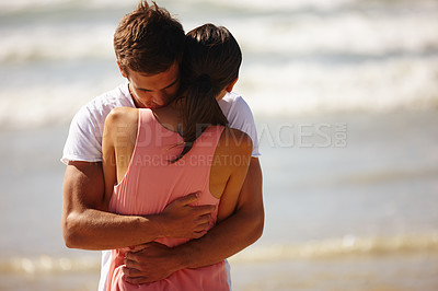 Buy stock photo Cropped shot of a young man comforting his girlfriend while standing on the beach