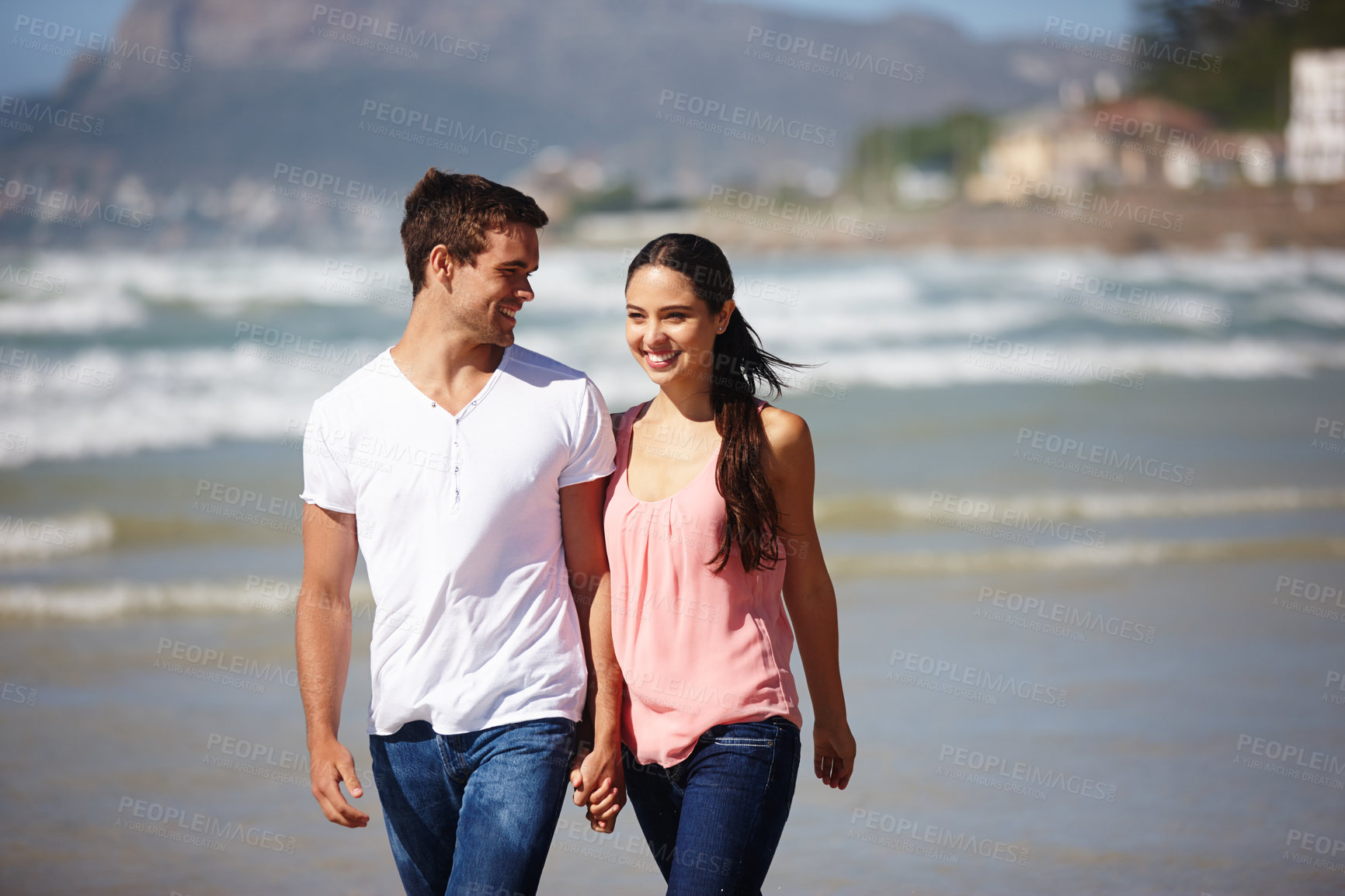 Buy stock photo Happy couple, holding hands and walking on beach with love, care or support on outdoor holiday in nature. Young man and woman with smile for embrace, relationship or weekend together by ocean coast