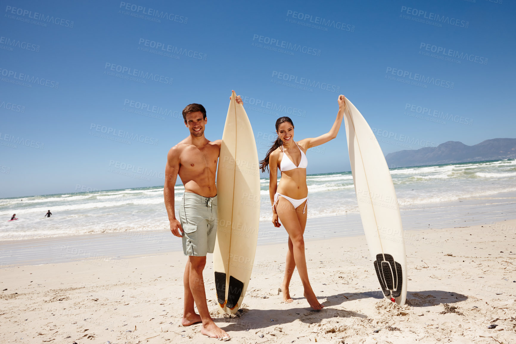 Buy stock photo Shot of a young couple holding surfboards at the beach