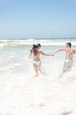 Buy stock photo Couple, water and splash at beach with playing for bonding, summer vacation and anniversary getaway. Man, woman and love by ocean with rear view for running, healthy relationship and holding hands