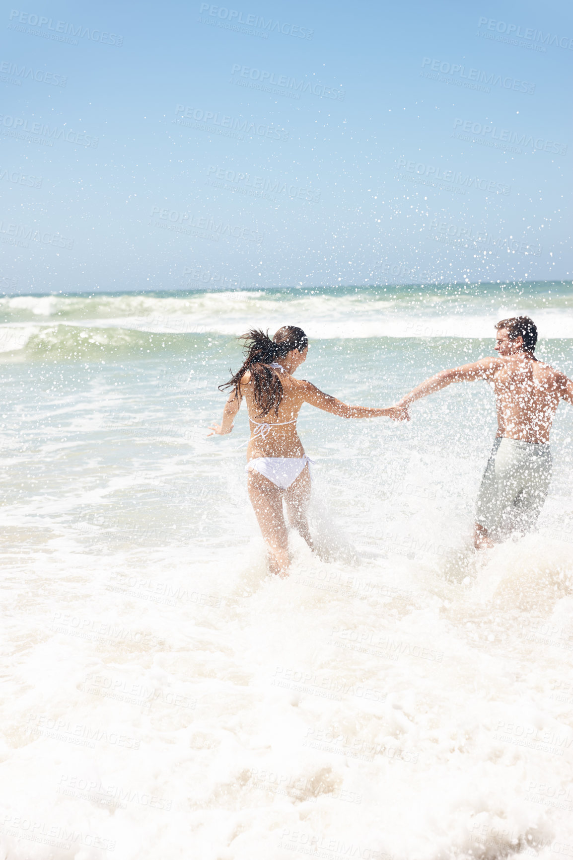 Buy stock photo Couple, water and splash at beach with playing for bonding, summer vacation and anniversary getaway. Man, woman and love by ocean with rear view for running, healthy relationship and holding hands