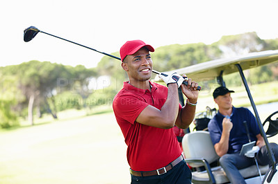 Buy stock photo Shot of a young man taking a shot while his friend congratulates him from the golf cart in the background