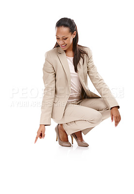 Buy stock photo Full length shot of an attractive young woman in a suit crouching down and pointing towards the ground isolated on white