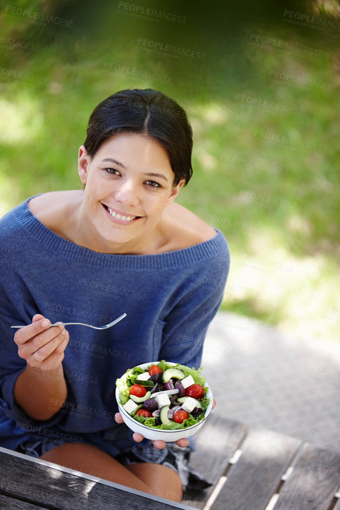 Buy stock photo Cropped shot of an attractive woman sitting in a garden and having a fresh salad 