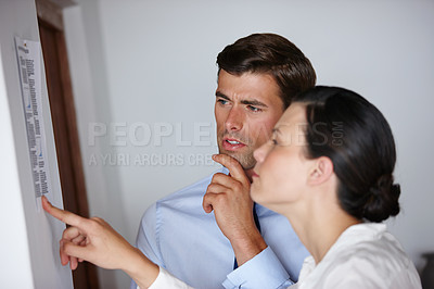 Buy stock photo Cropped shot of two business colleagues looking at a list on a wall