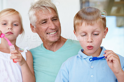 Buy stock photo Grandfather, kids and bubbles with bonding in home for child development with retirement. Grandpa, grandkids and fun for relax with relationship with smile for happiness, positivity and happy family