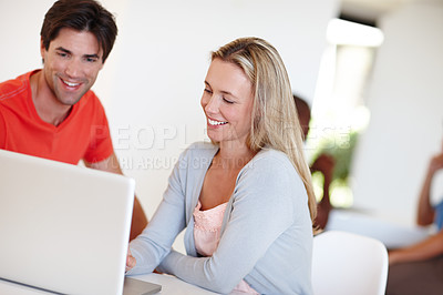 Buy stock photo Shot of two business colleagues using a laptop in an informal office