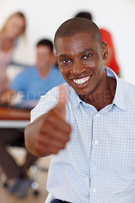 Buy stock photo Portrait of a handsome designer showing thumbs up while his colleagues work in the background