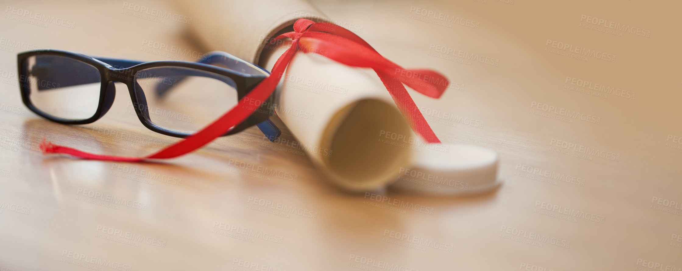 Buy stock photo Shot of a pair of glasses next to a diploma