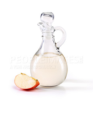 Buy stock photo Studio shot of a jug of apple cider vinegar with a slice of apple beside it