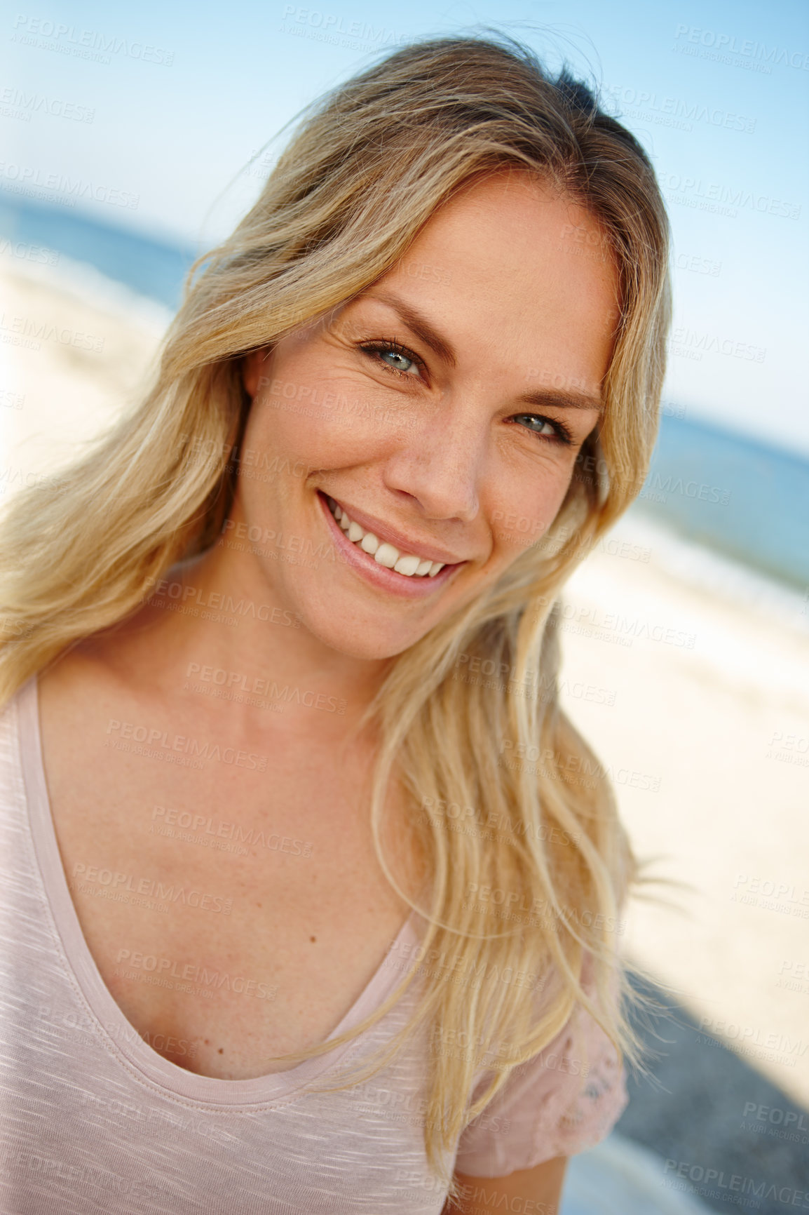 Buy stock photo Head and shoulders portrait of an attractive young woman standing on a sunny beach
