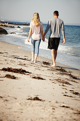 Buy stock photo Couple, walking and holding hands on sand of beach, peace and travel to nature for holiday. People, back and calm on weekend trip or vacation, love and date for relationship or marriage and ocean
