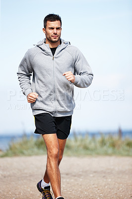 Buy stock photo Shot of a handsome young man running on the beach