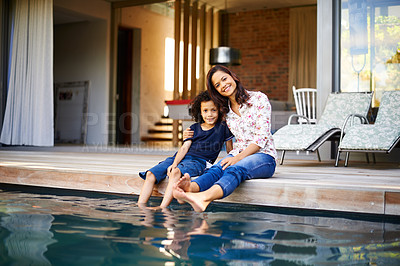 Buy stock photo Shot of a mother and son dipping their feet into the pool on the patio