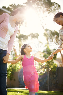 Buy stock photo A cute little girl being swung by her mother and grandmother in the garden