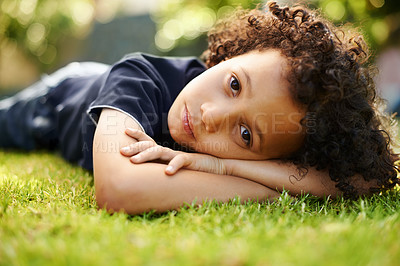 Buy stock photo A cute little boy lying down on the grass in the garden